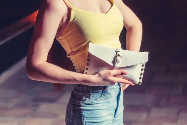 Vue latérale de la jeune femme à la mode avec embrayage dans la ville de nuit — Photo