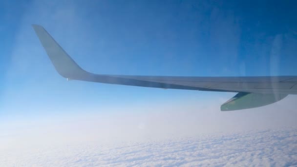 Flugzeugflügel fliegt über Wolkendecke, Blick durch dreckiges Fenster mit Spiegelungen — Stockvideo