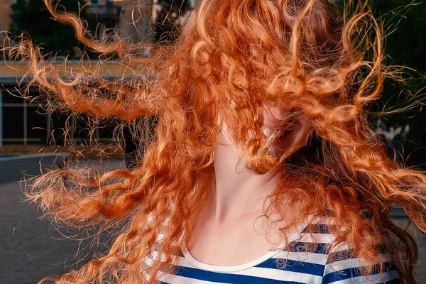 Faceless shot of red haired girl with her curly hair fly in air while she shaking her head — Stock Photo, Image