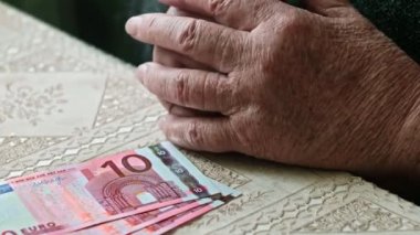 Üst düzey kadın endişeyle masada parmak ve üç on euro banknot ile oynarken elinde