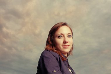 Kırmızı kafa kadınlara karşı bulutlu akşam gökyüzü gülümseyen.