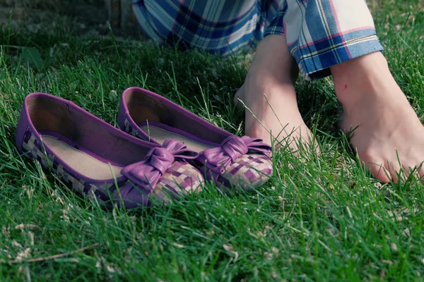 Barefoot women sitting on grass cross legged and her shoes near, a lot of copyspace — Stock Photo, Image