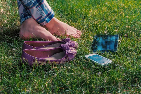 赤脚女孩在草地上放松盘腿与平板电脑和智能手机 — 图库照片