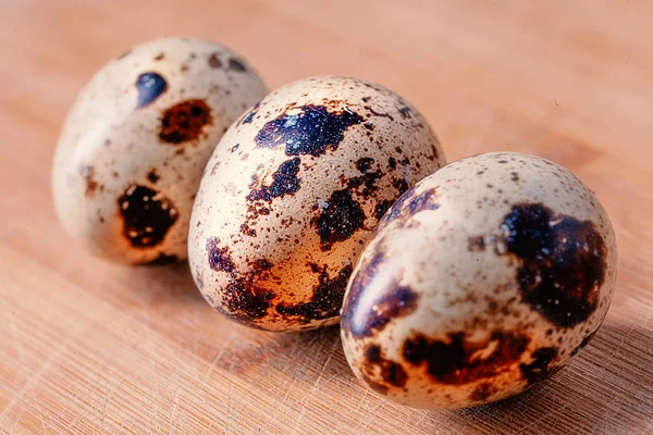 Three quail eggs on wooden board — Stock Photo, Image