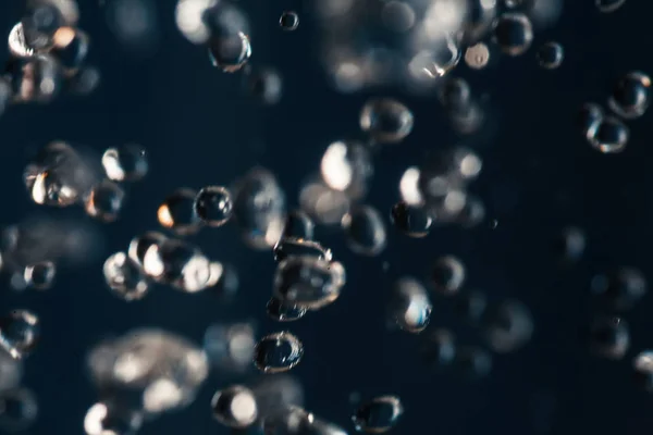 Small water drops frozen in an air on dark blue — Stock Photo, Image