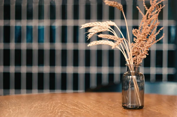 Planta seca e spiklets em frasco de vidro decorar em mesa de madeira no café contra a parede preta, ideia de decoração do café vintage — Fotografia de Stock