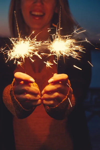 Close-up of happy woman with bright bruning sparklers in the night — Stock Photo, Image