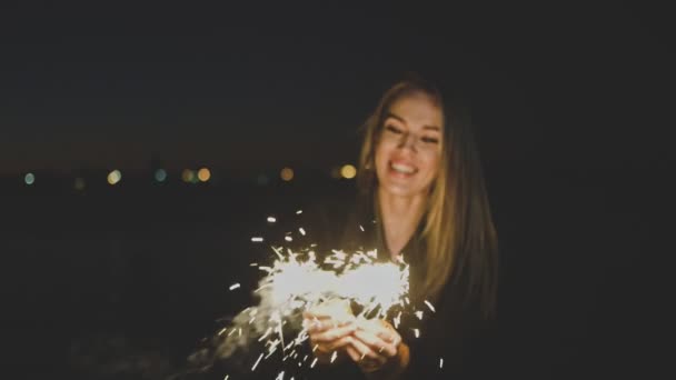 Joven mujer atractiva celebrando la celebración de la celebración de destellos en sus manos, disparo en slomo, retro gradación de color, imágenes borrosas . — Vídeo de stock