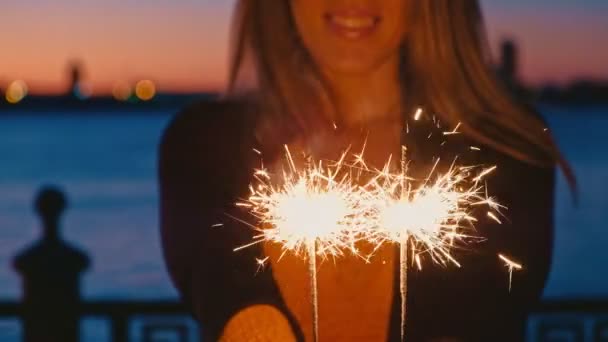 Mulher mão segurando sparkler ao ar livre na frente do céu por do sol — Vídeo de Stock