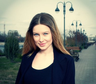 Sarı saçlı kadın gülümseyerek tonda instagram stil görüntüde açık havada park önden görünüm baş ve omuzlar shot