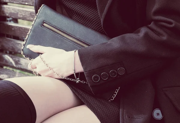 Mode jonge vrouw bedrijf zwarte portemonnee clutch in close-up van de hand. Instagram stijl blik. — Stockfoto