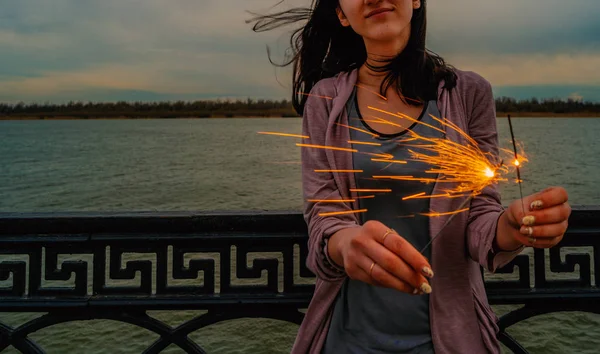 Alone girl standing in waterfront area with burning bengal lights — Stock Photo, Image