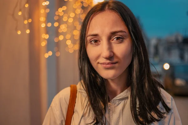 Calmo rosto menina na cidade da noite com guirlandas desfocadas iluminadas no fundo — Fotografia de Stock