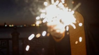 Bulanık Bengal ışıkları yavaş çekim videosunda genç bir kadının ellerinde yanıyor.