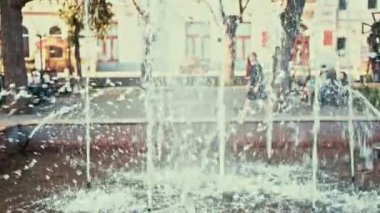 Şehir parkındaki fıskiyede yazın arka planda ağır çekimde yürüyen tanınmayan genç bir kız vardı.