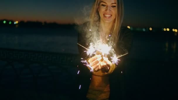 Blond haired girl celebrating new year s eve with bengal lights Beautiful woman holding a sparkling sticks at party night slomo. — Stock Video