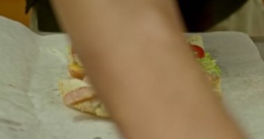 Sandviç hazırlama işçisi eti ve taze kesilmiş sebzeler el atış ile doldurulmuş.
