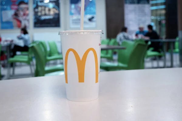 Astrakhan, Russia 13 feb 2019: McDonalds da asporto tazza di cola sul tavolo nel centro commerciale. logo del ristorante fast food McDonalds in giallo — Foto Stock