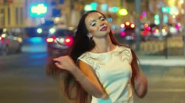 arka plan üzerinde şehir trafik ile onun uzun kahverengi kıllar ile oynarken gece şehirde gülümseyen kız