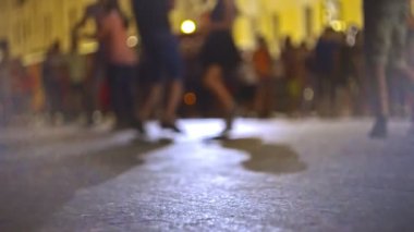 Arka planda odaksız çiftler sokakta salsa yapıyor.