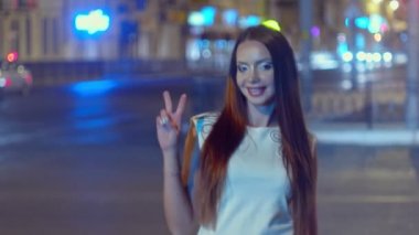 Arka planda bulanık ışıklarla V işaretini gösteren el kamerası görüntüsü.