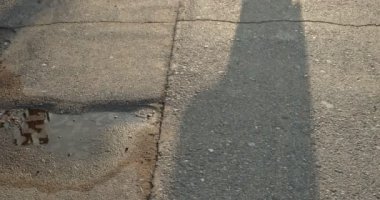 Siluet gölgesi tanınamaz halde güneş ışığında sokakta yürüyor.
