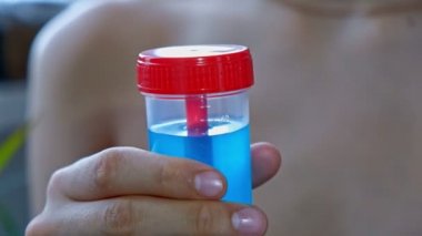 Mavi sıvı ile test tüpü tutan çocuk