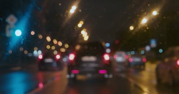 Coches de movimiento lento con luz trasera encendida bajo la lluvia mirar a través de la ventana mojada — Vídeos de Stock