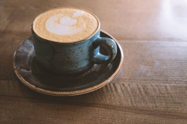 Vintage görünümlü Masa üzerinde köpük yan görünümünde mükemmel latte sanat ile Kahve fincan