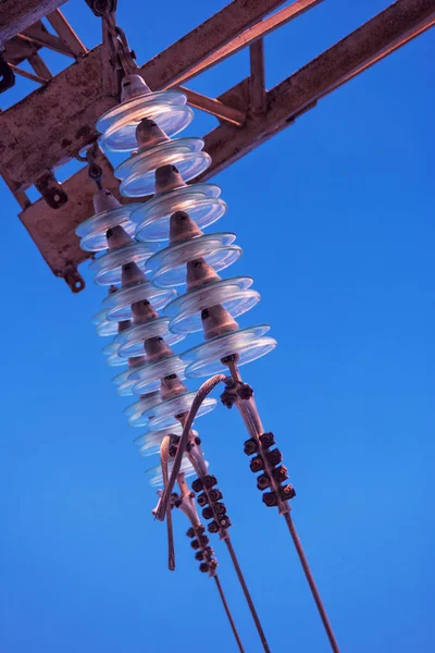 Vysokonapěťové elektrické izolátorské zařízení vyrobené ze skla na elektrické lince proti modrému nebi — Stock fotografie