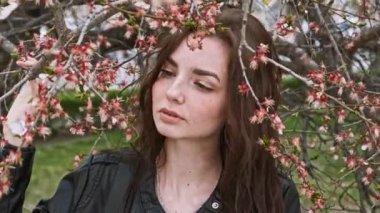 Sevimli kız çiçek açan kiraz ağacı dalları ile poz yüzünü obout