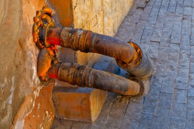 Duvara bağlı iki bükülmüş sıcak su borusu