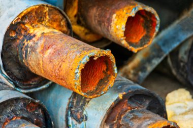 Closeup of Stack of corroded steel pipes with worn insulation industrial background. Rusty waterpipes stacked up clipart