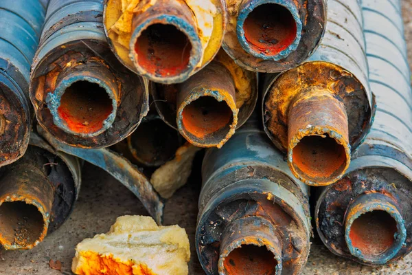 Reparación de tuberías de agua. Tubo de acero oxidado grande con aislamiento en el sitio de construcción en una envoltura de tubo de plástico que yace en el patio un montón horizontalmente. Antiguo oleoducto oxidado apilado — Foto de Stock