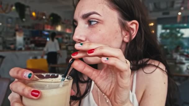 Девушка пьет кофе в столовой с соломенным профилем — стоковое видео