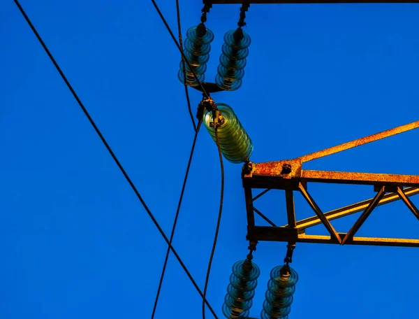 Sada skleněných elektrických izolátorů namontovaných na rezavě energetické věži — Stock fotografie