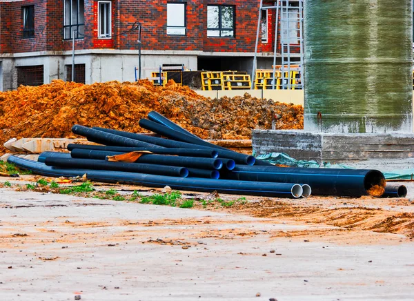 Canteiro de obras com alguns tubos deitados na terra — Fotografia de Stock