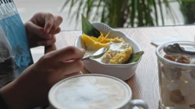 Önde duran kahve fincanıyla tabakta tatlı yiyen çocuk.