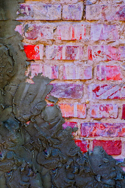 Old red brick wall half covered with fresh wet cement plaster