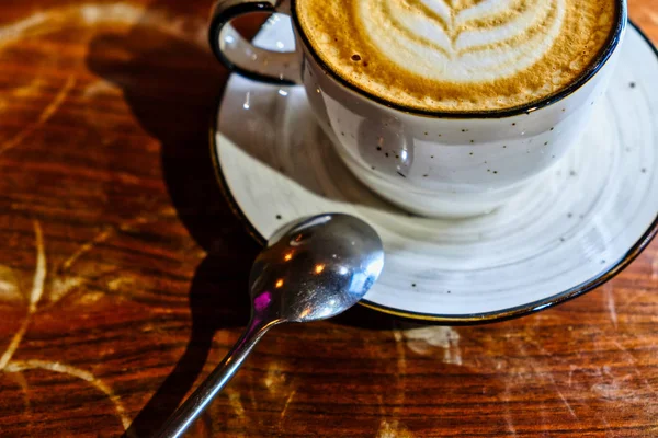 Coffee cup with cappuccino on the worn polished tabletop, detail above view — Stock Photo, Image