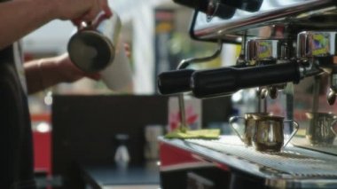 Barista kafede kahve yapıyor. Barista kahve üzerine süt çizer - kapuçino için latte sanatı yapar