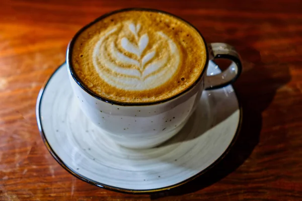Cuo di caffè con latte art sulla parte superiore schiumosa sul piano del tavolo — Foto Stock