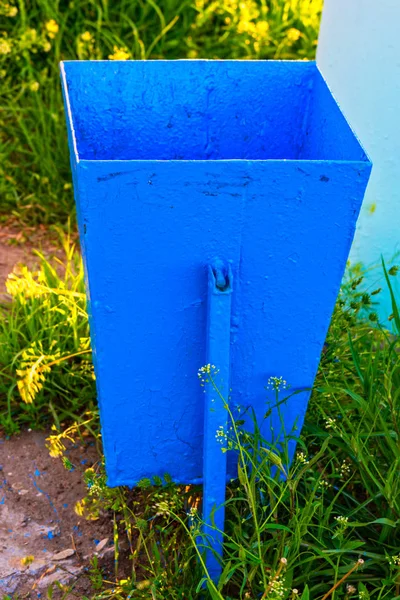 Lege vuilnisbak geschilderd in fel blauwe kleur in de tuin — Stockfoto