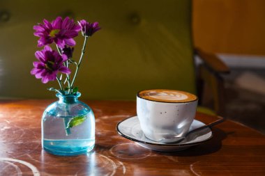 Şişe içinde masa wih çiçekler üzerinde cappuccino fincan