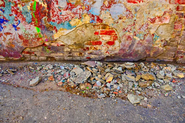 Damaged wall with building garbage beneath