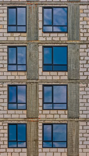 Parede do moderno edifício de apartamentos com janelas apenas montadas com reflexão do céu — Fotografia de Stock