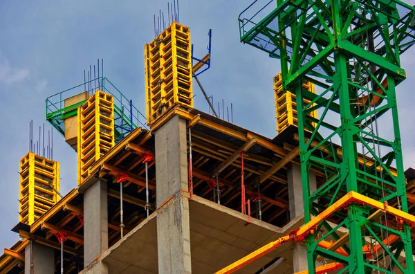 Apartment building construction work site with monolith concrete walls and crane painted in bright green color — Stock Photo, Image