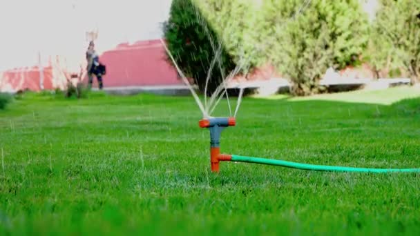 Sprinkler werken en vrouw lopen op achtergrond in slomo — Stockvideo