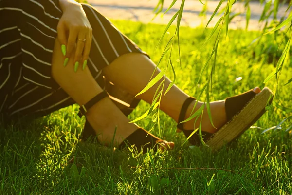 Beautiful legs in platform shoes on the grass baclit — Stock Photo, Image