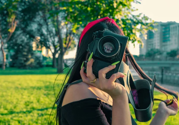 Menina asiática com câmera de filme no parque na hora do pôr do sol. Menina morena com fotocâmera na imagem colorida vintage — Fotografia de Stock